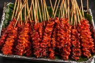 Grilled isaw on skewers, laid on banana leaf in a foil tray